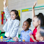 Two girls raised their hands in the classroom, which shows the adaptive learning concept.